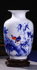 Un magnifique vase en porcelaine blanche et bleue orné de motifs floraux et d'oiseaux de couleur vive.