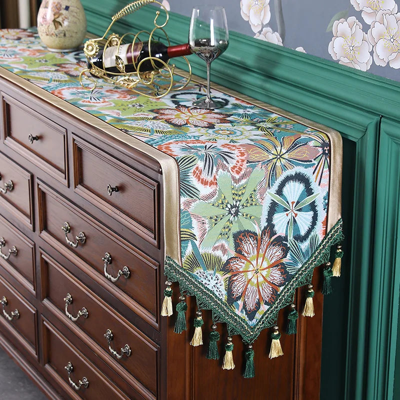 Sur ce meuble de rangement en bois sombre, un chemin de table coloré et orné de motifs floraux apporte une touche décorative élégante.