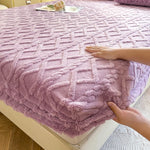 Une couverture douce et moelleuse de couleur violette avec un motif texturé géométrique décorant un lit.