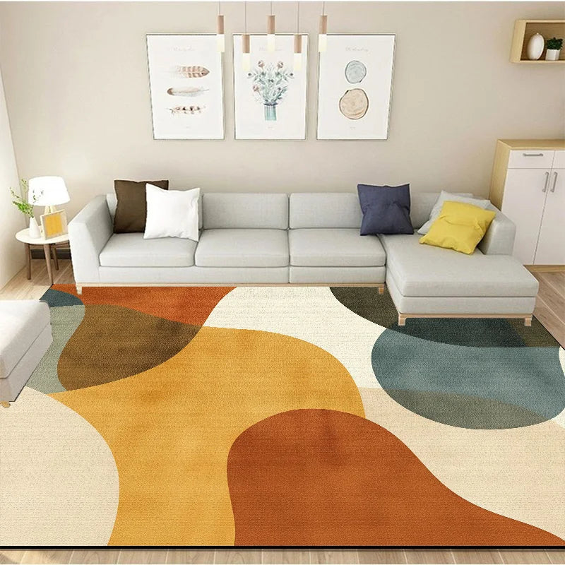 Un salon confortable avec un canapé gris et des coussins colorés, un tapis géométrique et des cadres décoratifs sur le mur.
