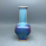 Un vase en céramique de couleurs bleu et violet, avec un col étroit et une forme élégante.