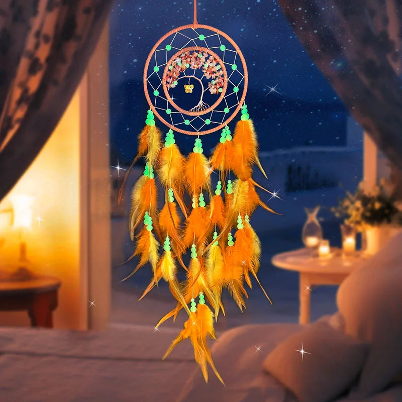 Une décoration murale fantaisiste, un attrape-rêves en forme de cercle avec des plumes orange, des perles vertes et une fleur au centre, suspendu devant un paysage nocturne étoilé.