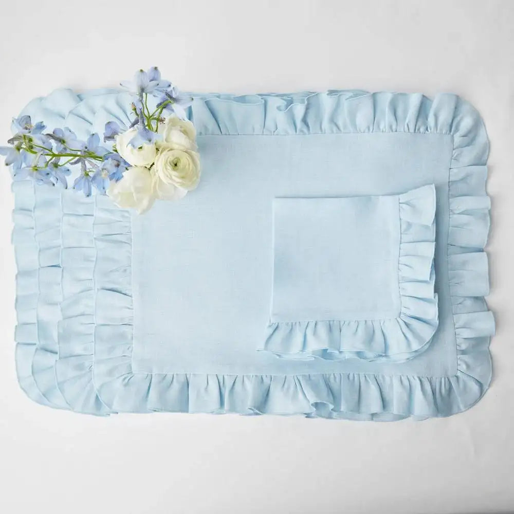 Coque de lit en satin bleu clair avec une bordure plissée et une fleur blanche posée sur le côté.