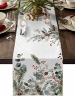Une nappe de table blanche ornée de motifs naturels hivernaux tels que des branches de sapin, des baies rouges et des cônes de pin, créant une atmosphère festive pour une réception.