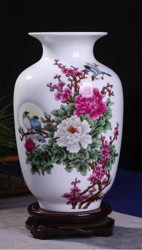 Vase en porcelaine blanche décoré de fleurs de pivoines roses et de motifs d'oiseaux sur un fond noir.