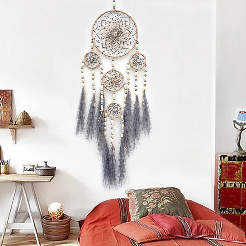 Un rêve captivant suspendu au mur, avec ses motifs géométriques, ses perles délicates et ses longues plumes grisâtres, apportant une touche ethnique et relaxante à l'espace.