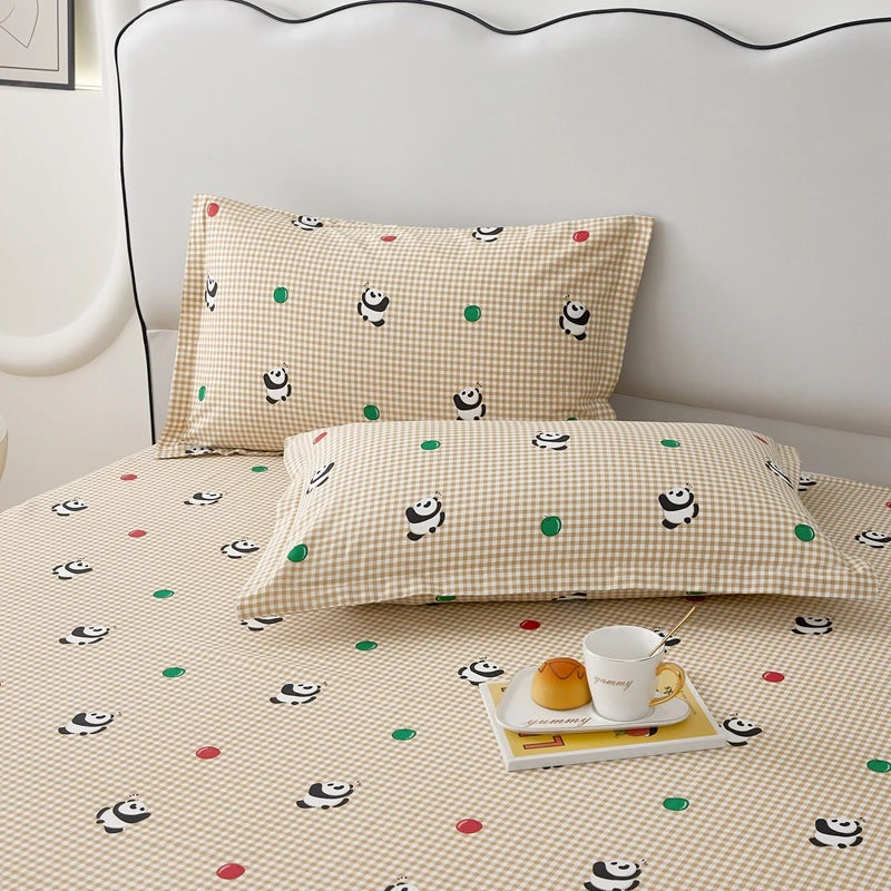 Une couverture et des oreillers motif visages souriants sur un dessus de lit beige à carreaux.