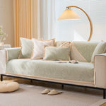 Un salon confortable avec un canapé beige décoré de coussins, une lampe sur pied à abat-jour crème et des rideaux beiges près d'une fenêtre.