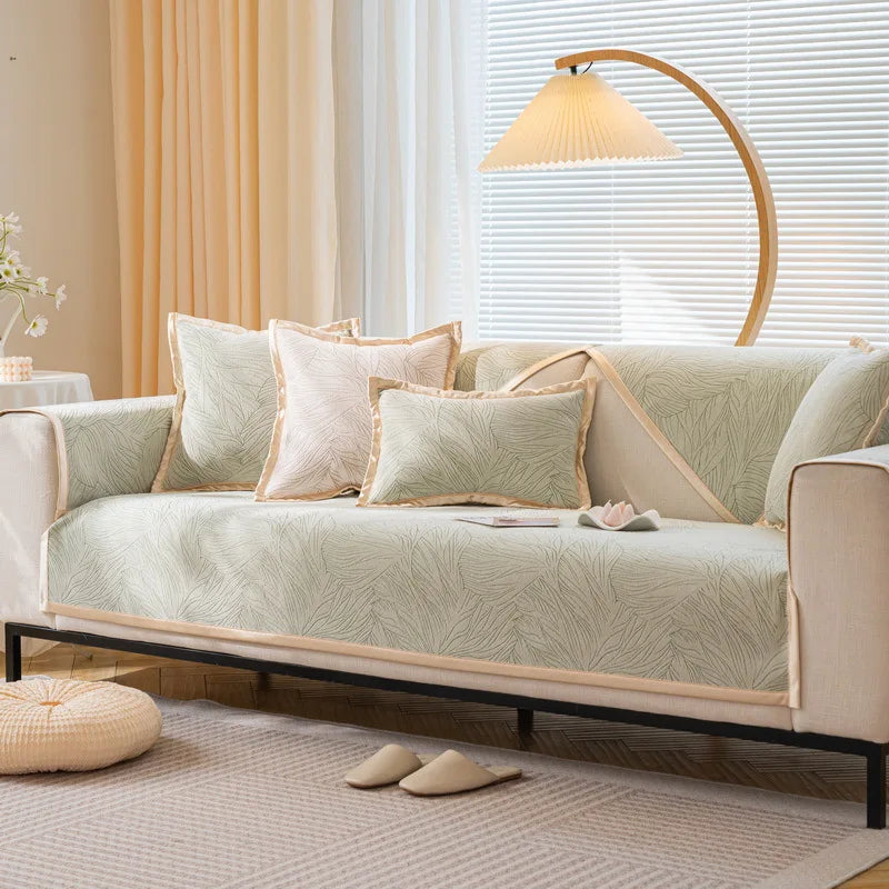 Un salon confortable avec un canapé beige décoré de coussins, une lampe sur pied à abat-jour crème et des rideaux beiges près d'une fenêtre.