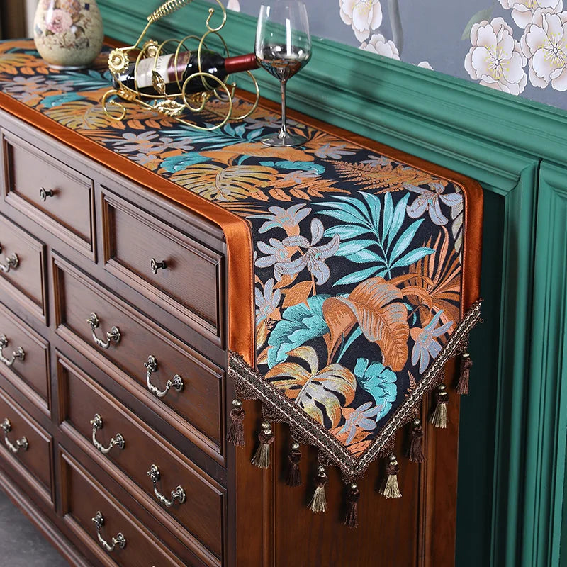 Un meuble à tiroirs de style vintage avec un chemin de table décoré de motifs tropicaux colorés et de pompons.