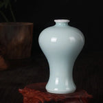 Un vase en céramique bleu clair posé sur un fond sombre.