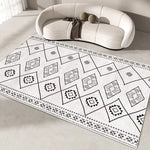 Tapis de sol à motifs géométriques monochromes, avec des carrés et des formes triangulaires, créant un design abstrait et épuré dans les tons de noir et blanc.