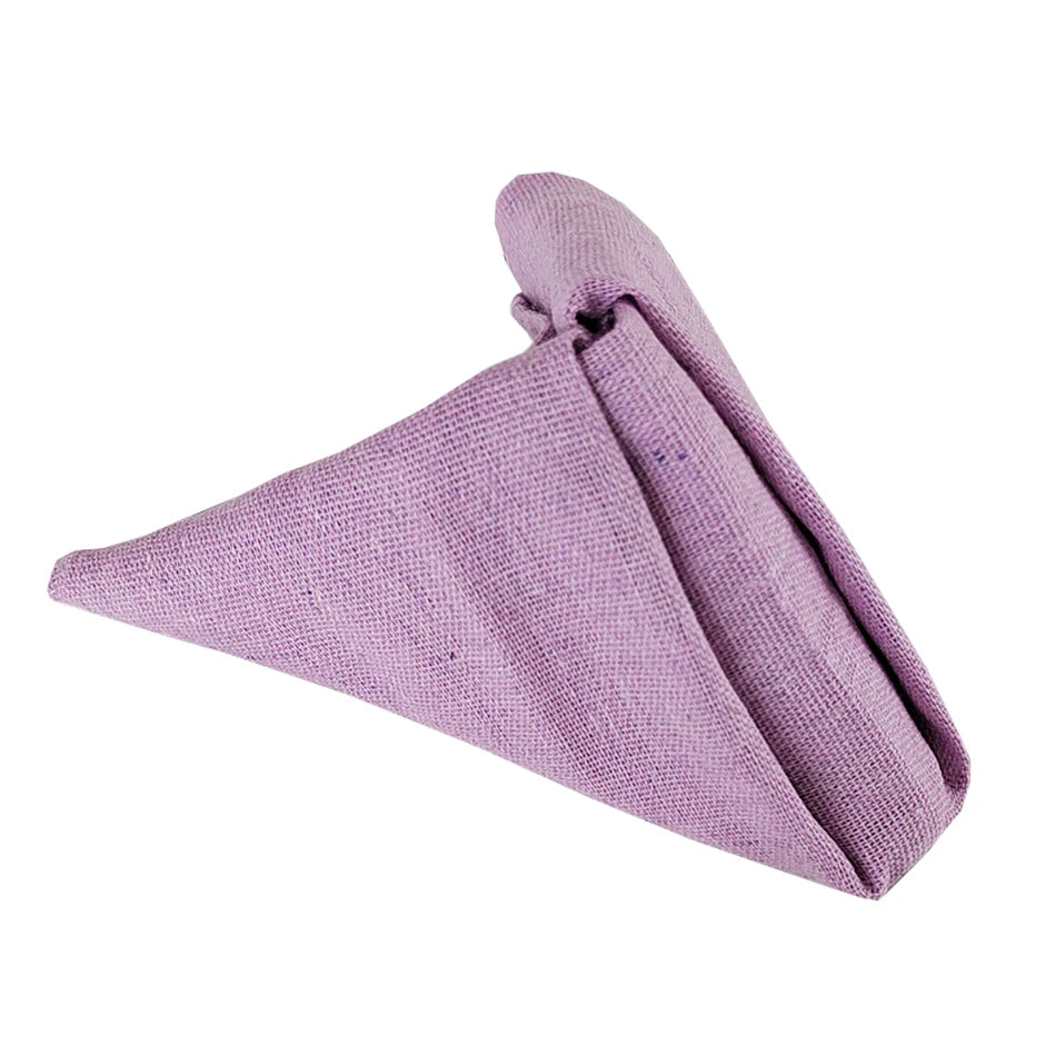 Une serviette de table pliée en triangle, d'une couleur lilas doux.
