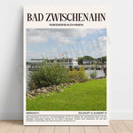 Photographie d'un quai paisible au bord d'un plan d'eau, entouré de végétation verdoyante et de bâtiments caractéristiques de Bad Zwischenahn, une ville allemande connue pour ses thermes et ses aménagements paysagers.
