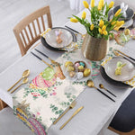 Cette image montre une élégante table de fête printanière, ornée d'un bouquet de tulipes jaunes dans un vase doré, de décorations de Pâques colorées et de couverts dorés sur une nappe fleurie.