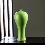 Vase en céramique de couleur vert clair posé sur une surface sombre.