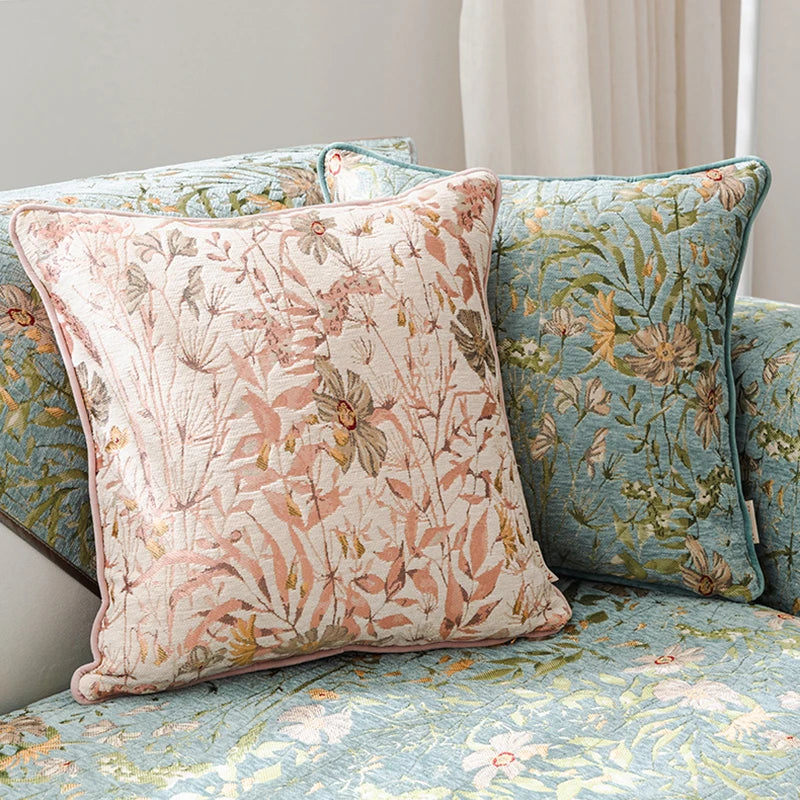 Des coussins décoratifs aux motifs floraux colorés, disposés sur un canapé, créent une ambiance chaleureuse et apaisante dans la pièce.