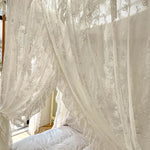 Intérieur luxueux avec des rideaux en dentelle blanche ornés de motifs floraux, créant une atmosphère élégante et romantique dans une chambre accueillante.