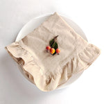 Sur un plat blanc, un linge de table beige porte quelques baies rouges et vertes.