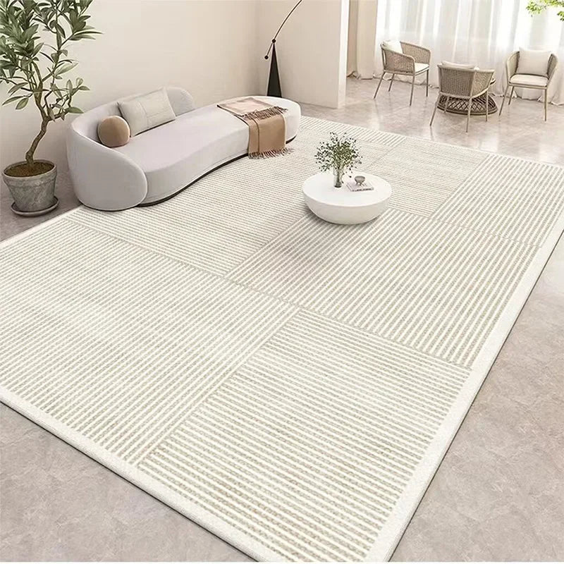 Un salon spacieux et lumineux, avec un canapé blanc, une table basse ronde et des chaises en rotin sur un sol carrelé à motifs géométriques, créant une atmosphère épurée et élégante.