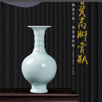 Vase en céramique blanc brillant sur une étagère en bois foncé, avec un texte chinois doré au-dessus.