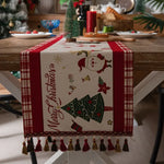 Un chemin de table de Noël décoré d'un motif de sapin de Noël et de figurines de Noël sur un fond bois.