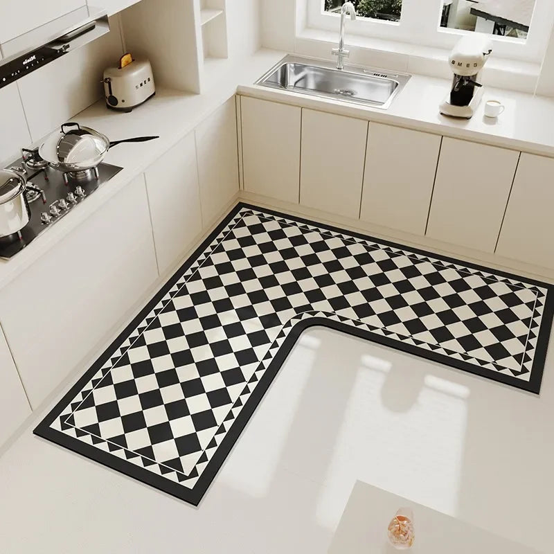 Le sol de la cuisine est recouvert d'un carrelage aux motifs géométriques noir et blanc, créant un contraste saisissant avec les meubles blancs et l'évier en métal.