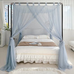 Chambre à coucher à thème romantique avec un lit à baldaquin, des rideaux aériens de couleur bleu clair et un couvre-lit blanc avec de la dentelle.