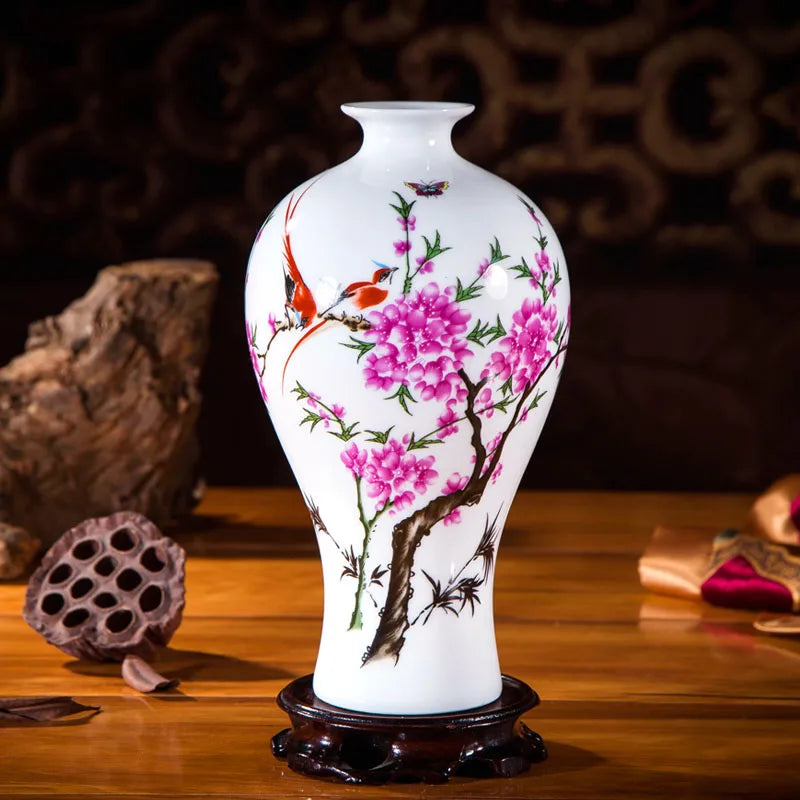 Un vase décoratif de style oriental, avec de magnifiques fleurs de cerisier roses peintes sur un fond blanc, et une scène d'oiseaux colorés au milieu, créant une œuvre d'art de porcelaine raffinée.