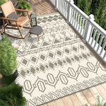 Tapis géométrique beige et gris sur un parquet en bois entouré de plantes tropicales sur un porche apaisant.