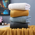 Des serviettes de bain moelleuses et colorées empilées les unes sur les autres, créant une belle composition de teintes chaudes et froides.