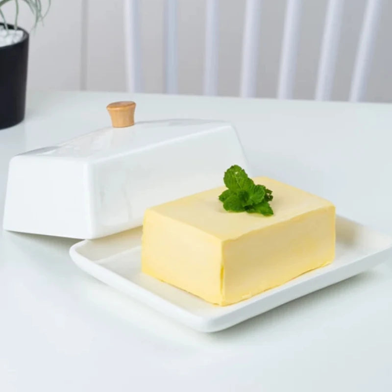 Beurrier en céramique blanche avec couvercle sur une table en bois