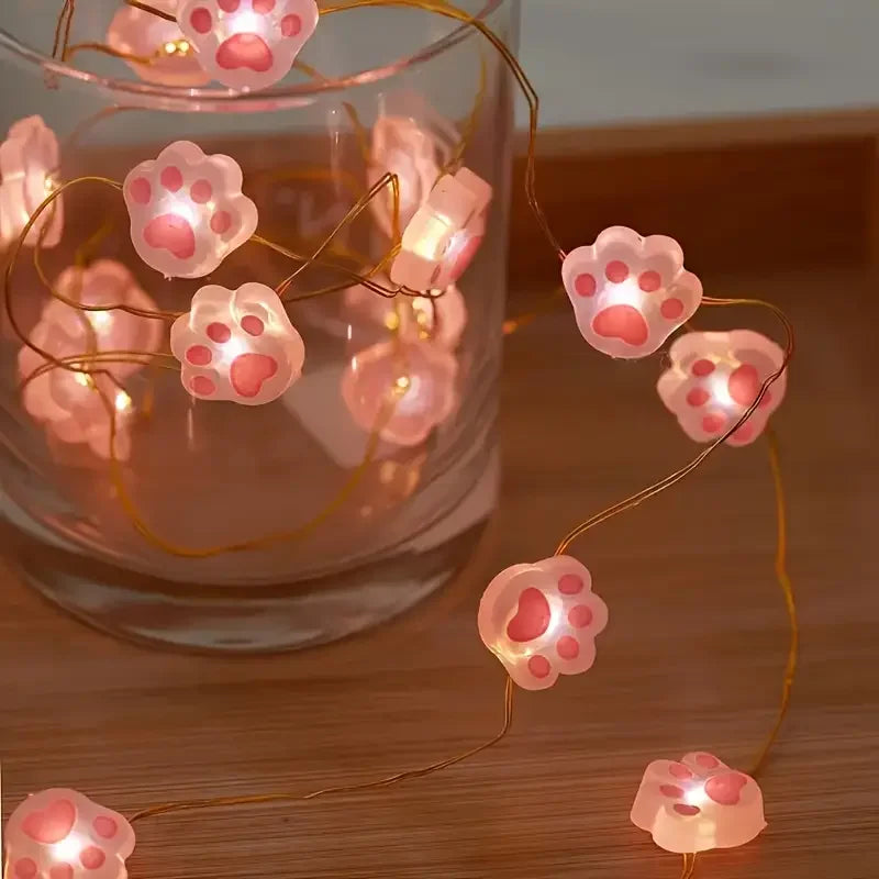 Guirlande lumineuse suspendue en forme de patte de chat rose allumée dans une chambre