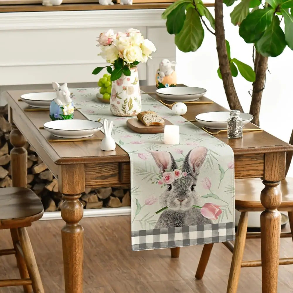 Une table de salle à manger élégante avec une décoration de Pâques, comprenant des fleurs, des lapins décoratifs et des accessoires de table coordonnés.