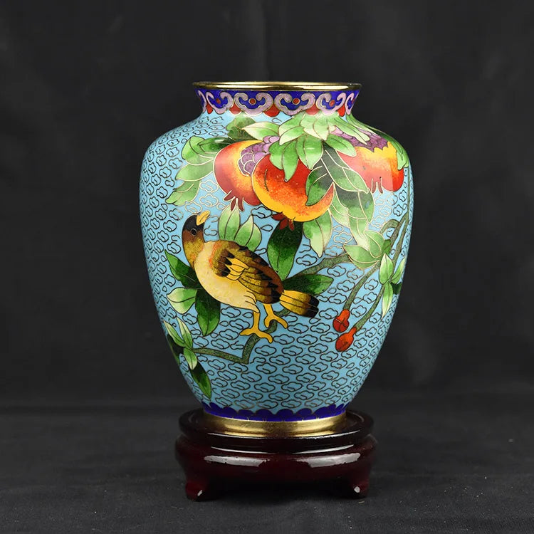 Un vase décoratif bleu et doré orné de motifs floraux et d'oiseaux colorés, créant une scène naturelle élégante et attrayante.