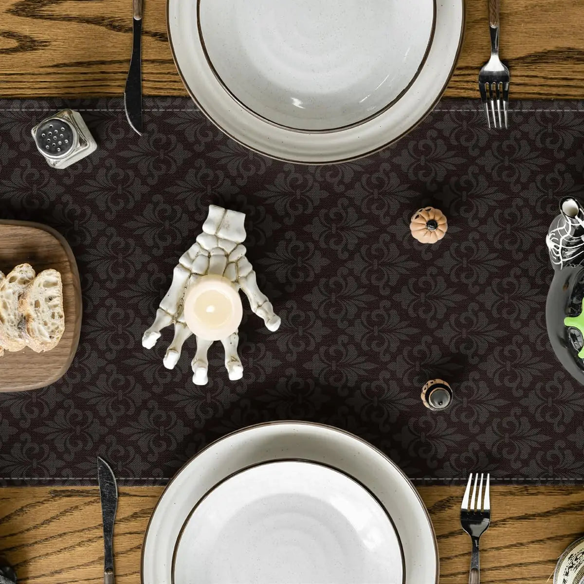 Une table de salle à manger avec des assiettes, des couverts et des éléments de décoration, sur un fond de motif sombre, créant une ambiance chaleureuse et conviviale.