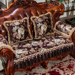 Un canapé en cuir brun richement orné de coussins et d'un couvre-lit brodé de motifs floraux élégants, créant une atmosphère de luxe et de sophistication dans la pièce.