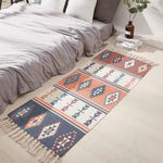 Un élégant tapis décoratif aux motifs géométriques colorés, posé sur le sol d'une chambre au style épuré, avec un lit confortable garni de draps gris.