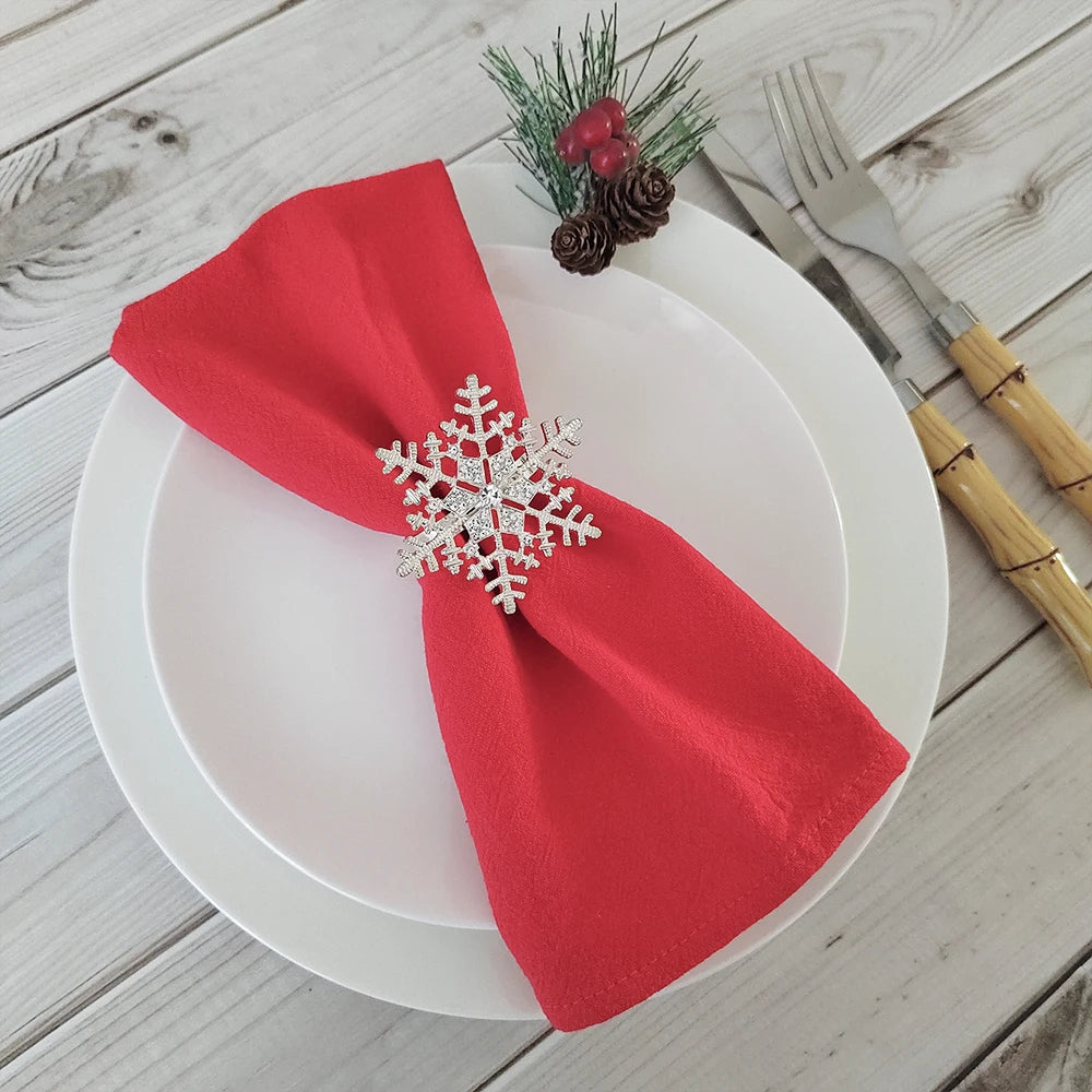 Assiette blanche avec serviette rouge et décorations de Noël sur une surface en bois.