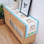 Une table de bureau décorative avec un plateau en bois et des motifs de pattes d'animaux peints dessus, entourée de plantes vertes et d'un cadre photo.