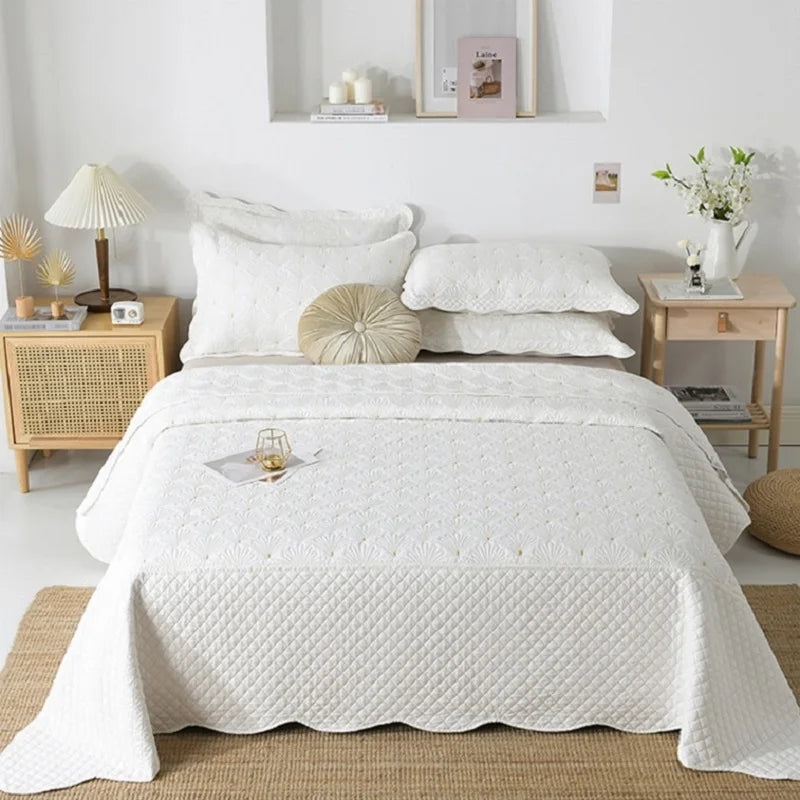 Détail de la broderie géométrique sur le couvre-lit blanc