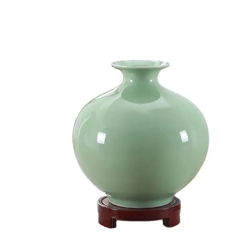 Vase en céramique de couleur vert menthe posé sur un support en bois.