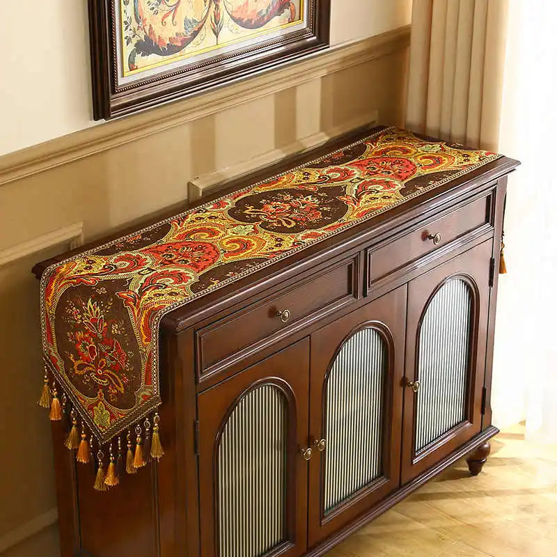 Buffet antique en bois sombre avec un superbe chemin de table en coton orné de motifs floraux aux couleurs vives.