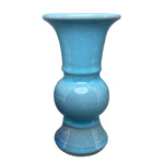 Vase décoratif en céramique brillante de couleur bleu turquoise, à la forme élégante et distinctive.
