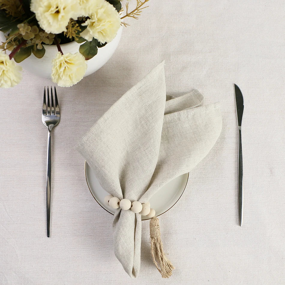 Une table dressée avec des fleurs, une serviette de table blanche et des couverts en métal, créant une atmosphère élégante et raffinée.