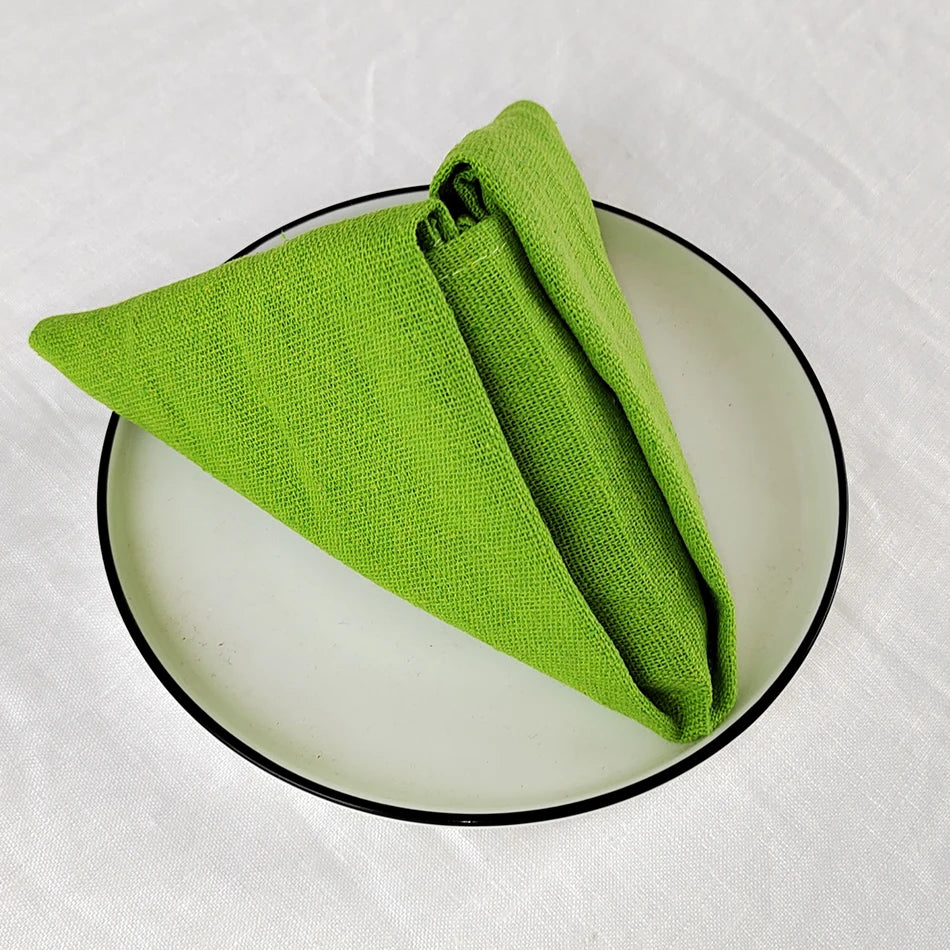 Un chiffon de cuisine vert vif plié sur une assiette ronde noire.