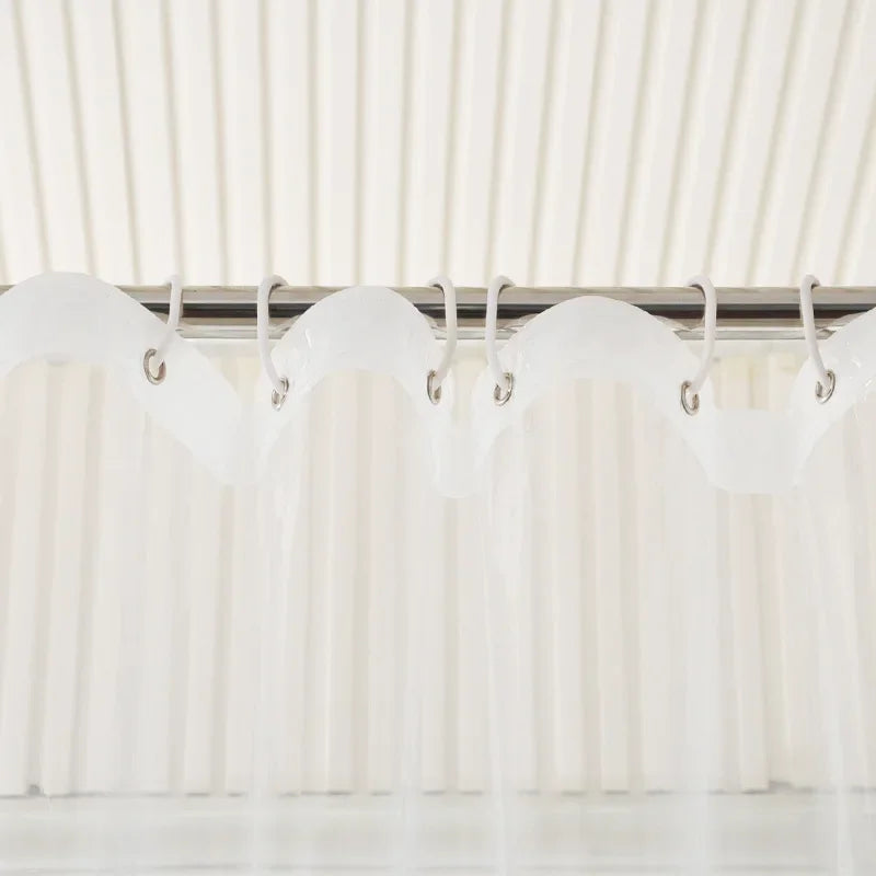 Rideau de douche transparent associé à des accessoires de salle de bain en bois clair
