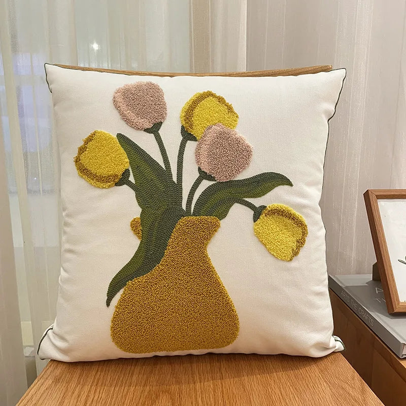 Coussin décoratif avec un motif de bouquet floral coloré dans un vase.