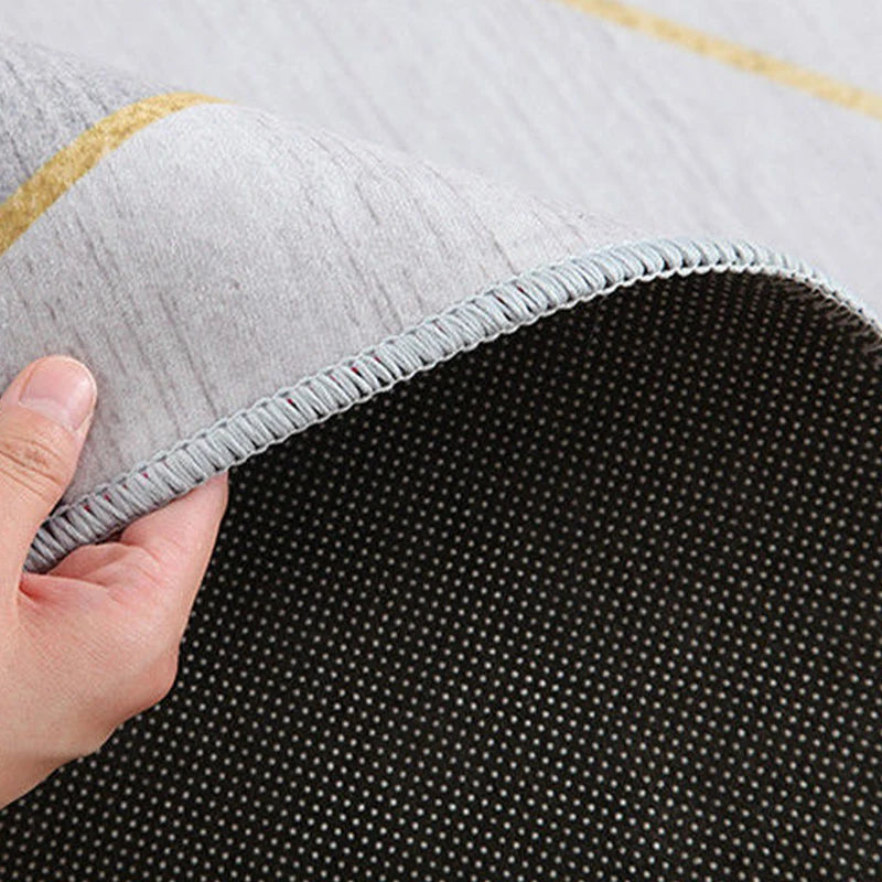 Gros plan sur le bord d'un tapis gris avec des motifs en nid d'abeille, montrant la solidité de la couture et de la construction.
