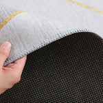 Gros plan sur le bord d'un tapis gris avec des motifs en nid d'abeille, montrant la solidité de la couture et de la construction.